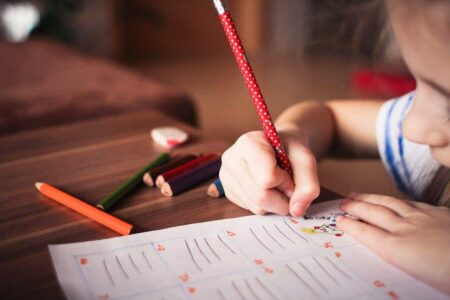 child writing with red pencil