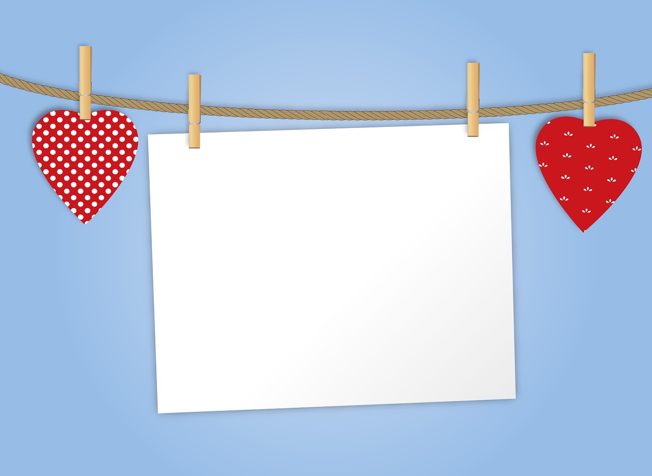 Blank white card pinned to a display cord with red hearts pinned on either side